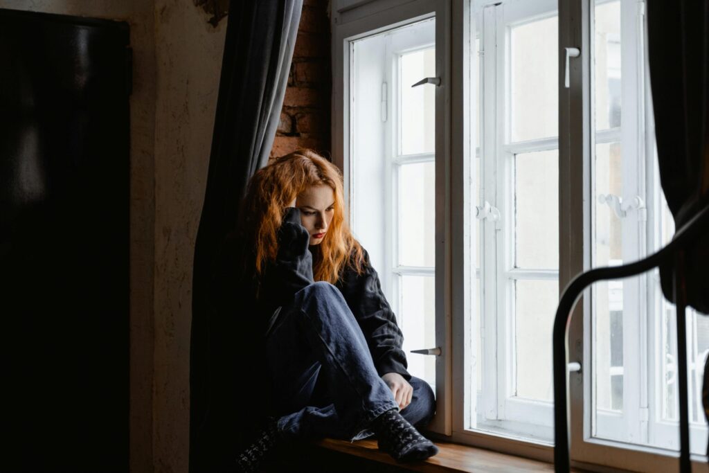pexels photo 7277896 7277896 A woman sits by a window, lost in deep thoughts and moody light.