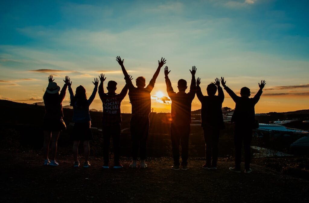 pexels photo 853168 A diverse group of friends raises their arms in celebration against a vibrant sunset backdrop.